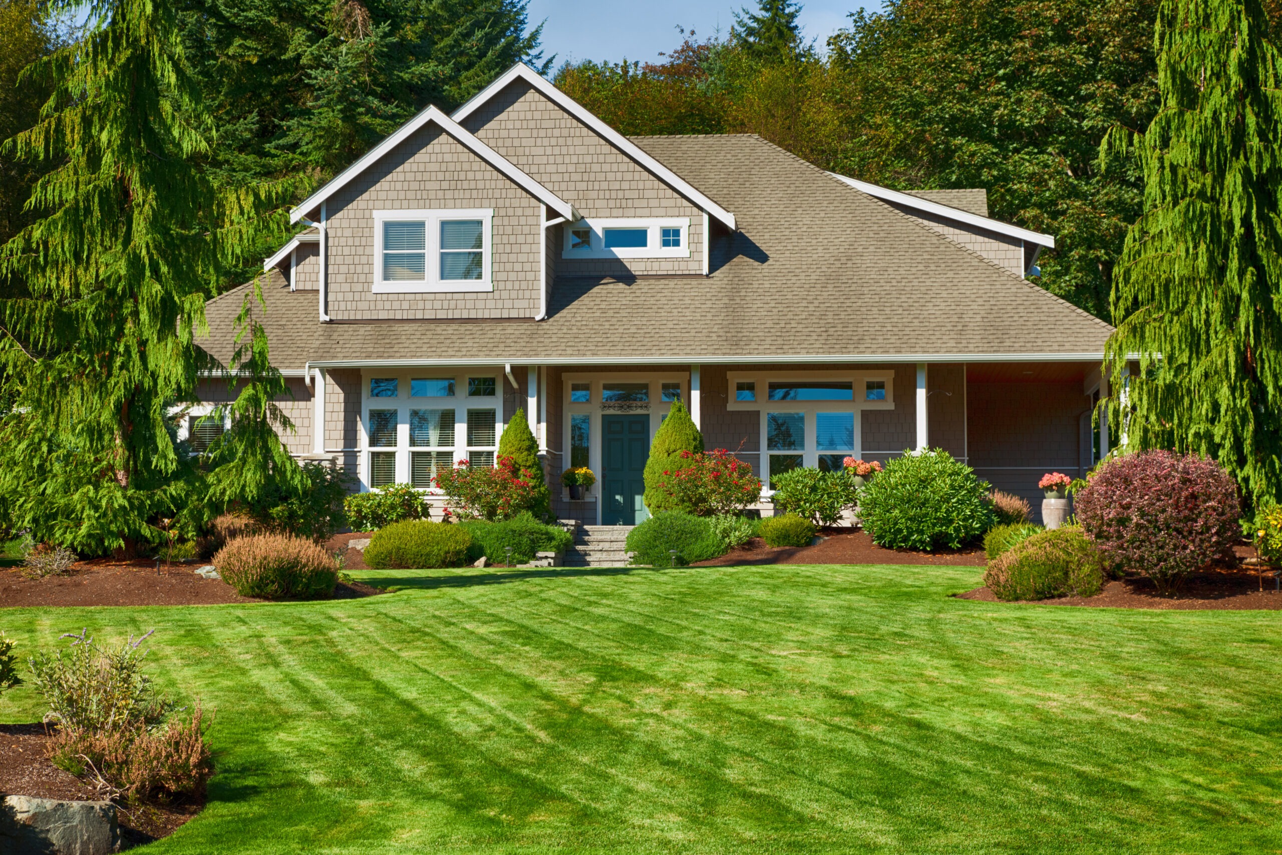 Modern, well-maintained house surrounded by lush greenery and landscaped gardens, showcasing curb appeal and tranquility.