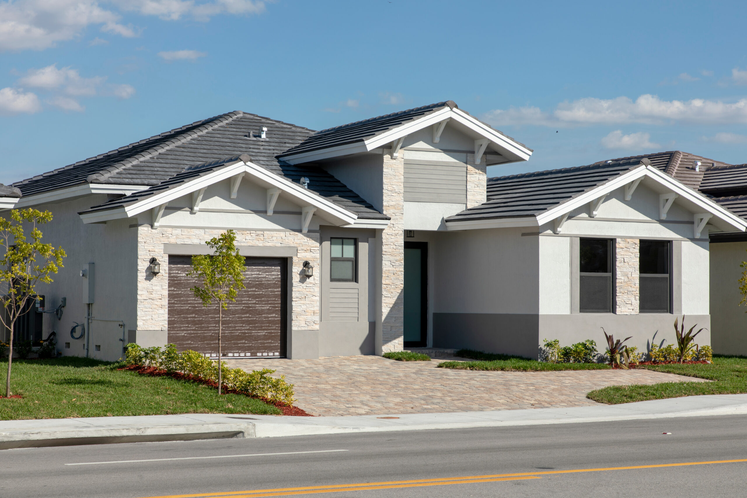 Modern single-family home with a stone-accented façade, a dark wood garage door, and landscaped front yard. Showcases contemporary architectural design.